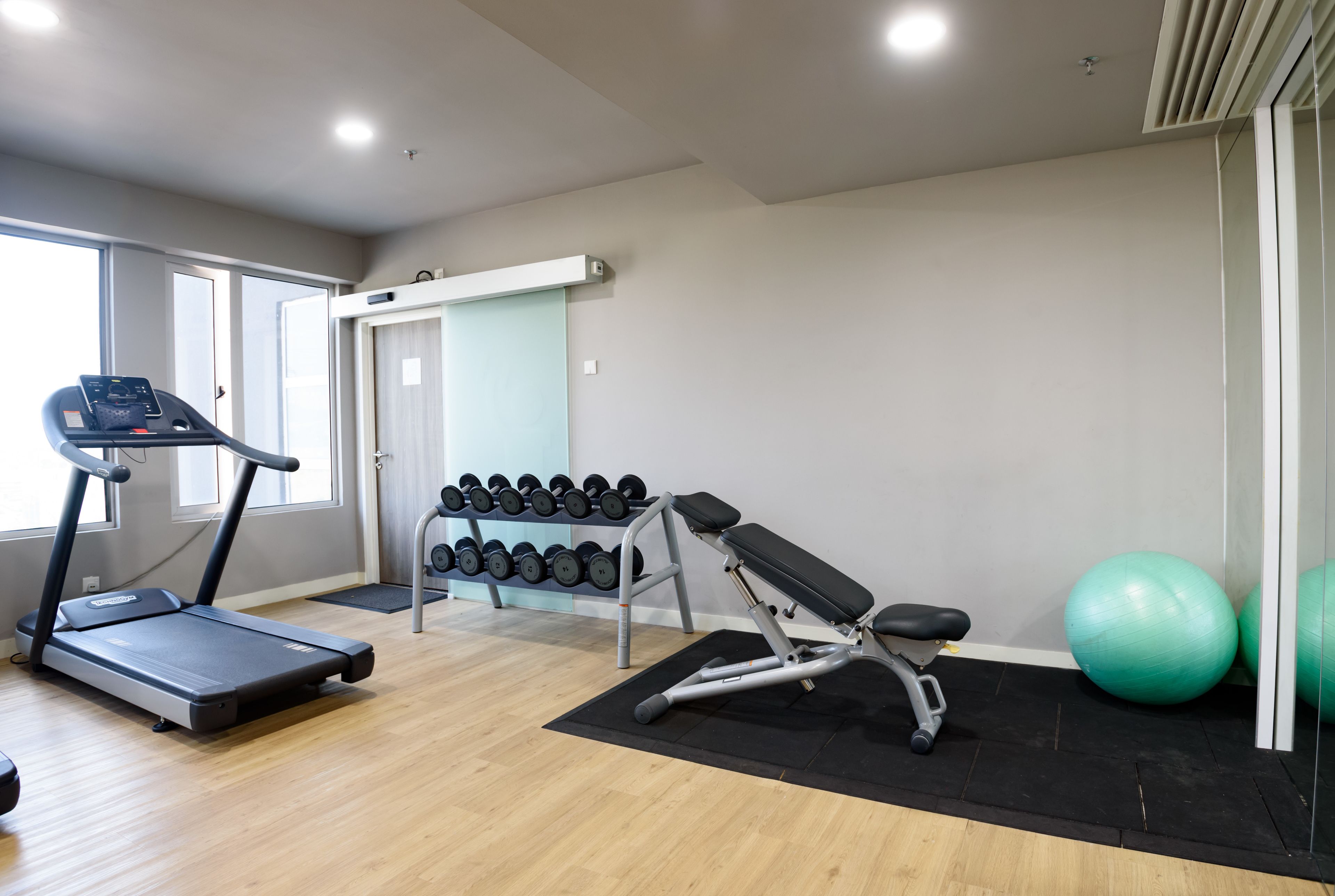 Ein Fitnessstudio mit Laufbändern, Hanteln, einer Langhantelbank und Trainingsbällen.