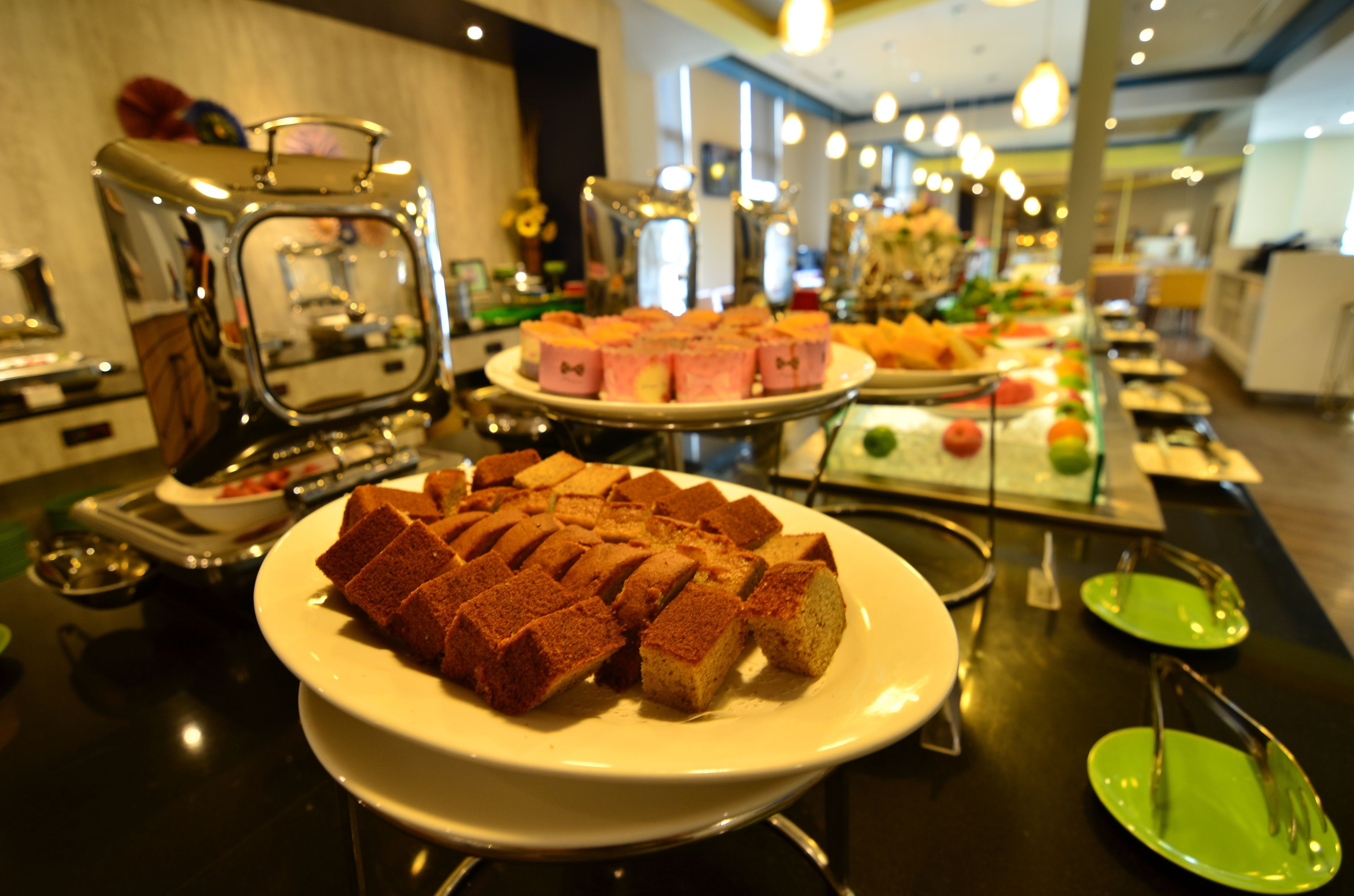 A buffet with various food items, including cakes and pastries, arranged on plates and serving stands.