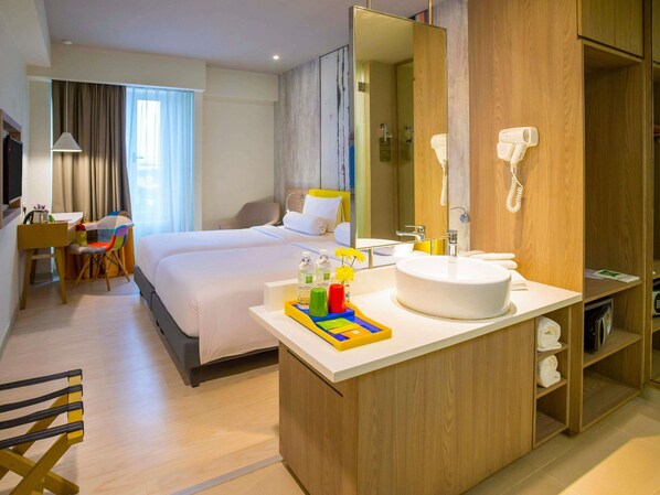 A hotel room with a bed, a desk, a chair, a bathroom with a sink, and a mirror. - ibis Styles Kuala Lumpur Sri Damansara (Batu Caves)