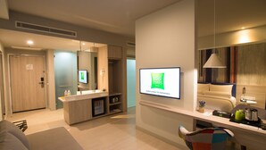 Een moderne hotelkamer met een grote spiegel, een flatscreen televisie, een bureau met stoel en een bank.
