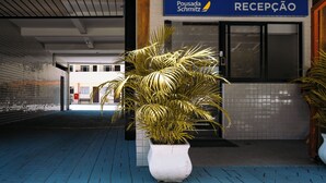 Ett receptionsområde med en skylt för Pousada Schmitz, en krukväxt och ett klinkergolv.