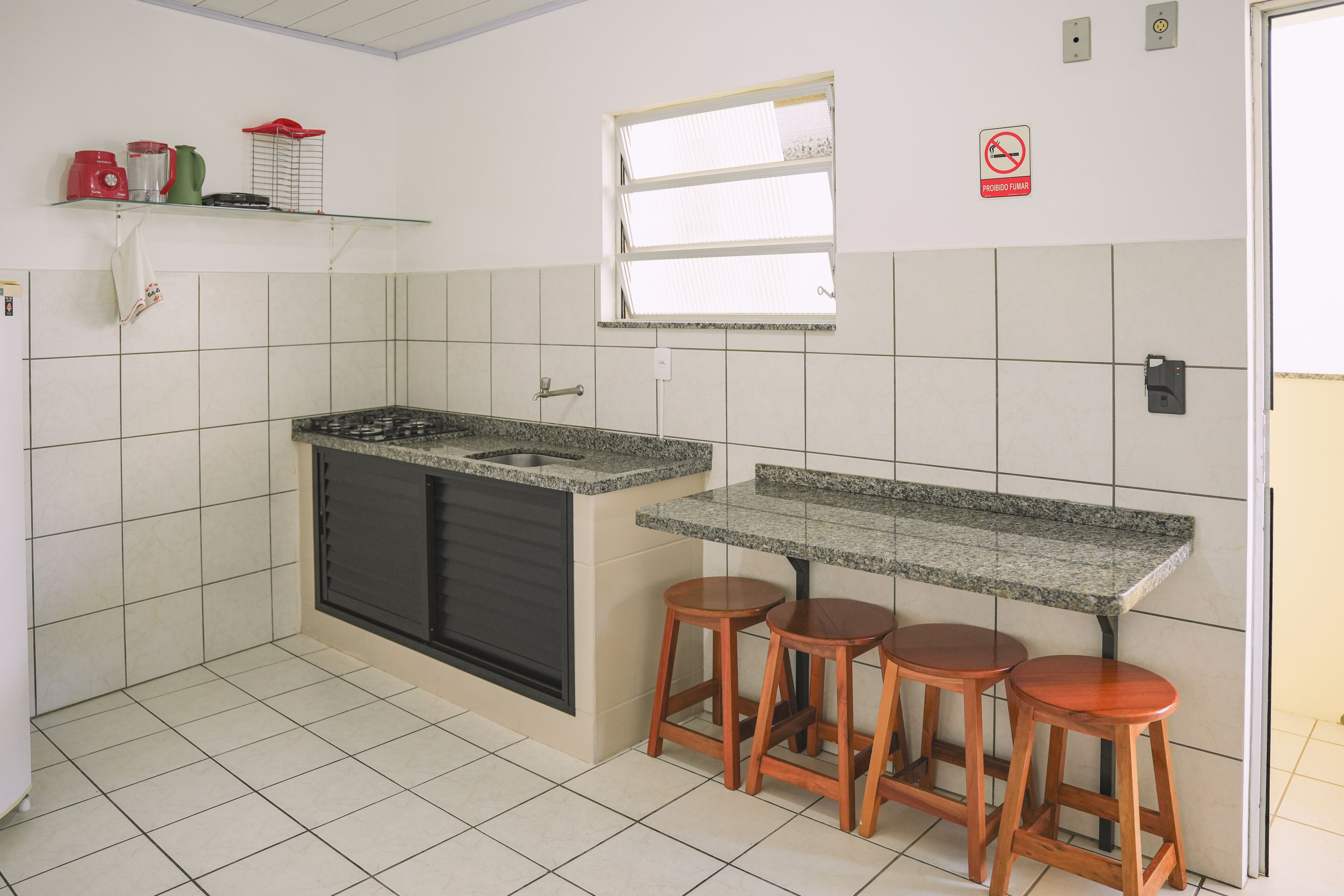 A kitchen with a granite countertop, two wooden stools, a window, and a 'no smoking' sign.