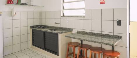 A kitchen with a granite countertop, two wooden stools, a window, and a 'no smoking' sign.