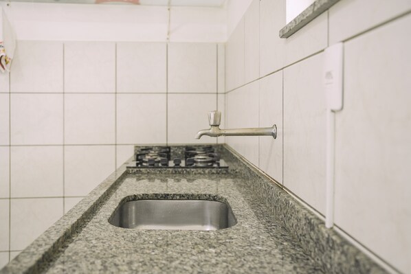 A kitchen with a granite countertop, stainless steel sink, and a gas stove.