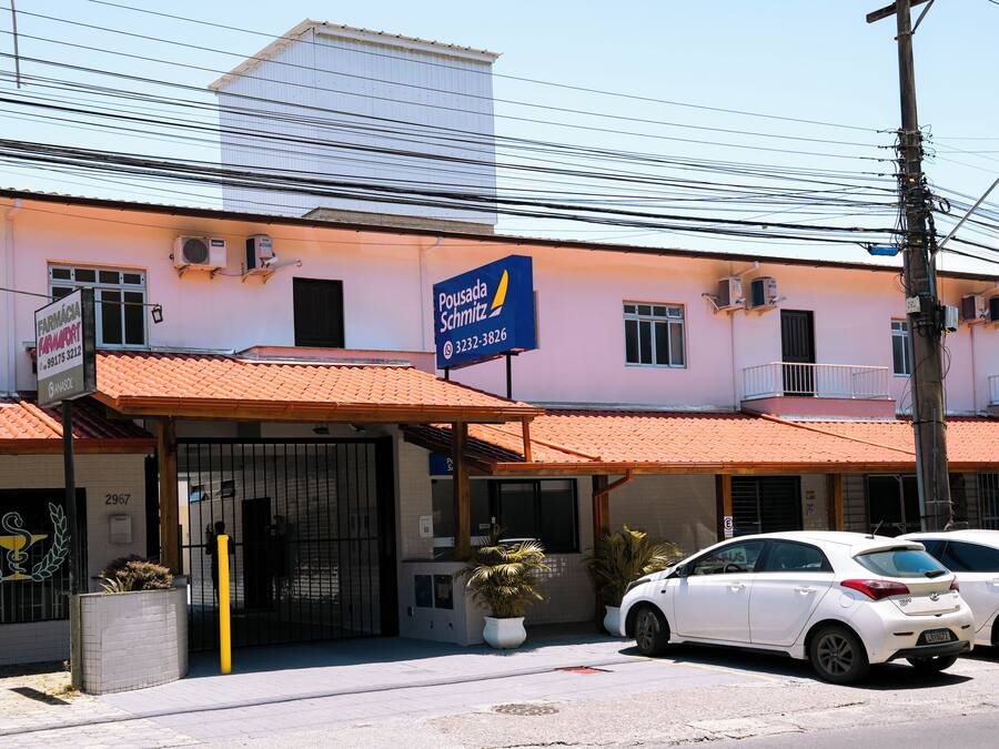 A building with a sign for 'Pousada Schmitz' and a gated entrance.