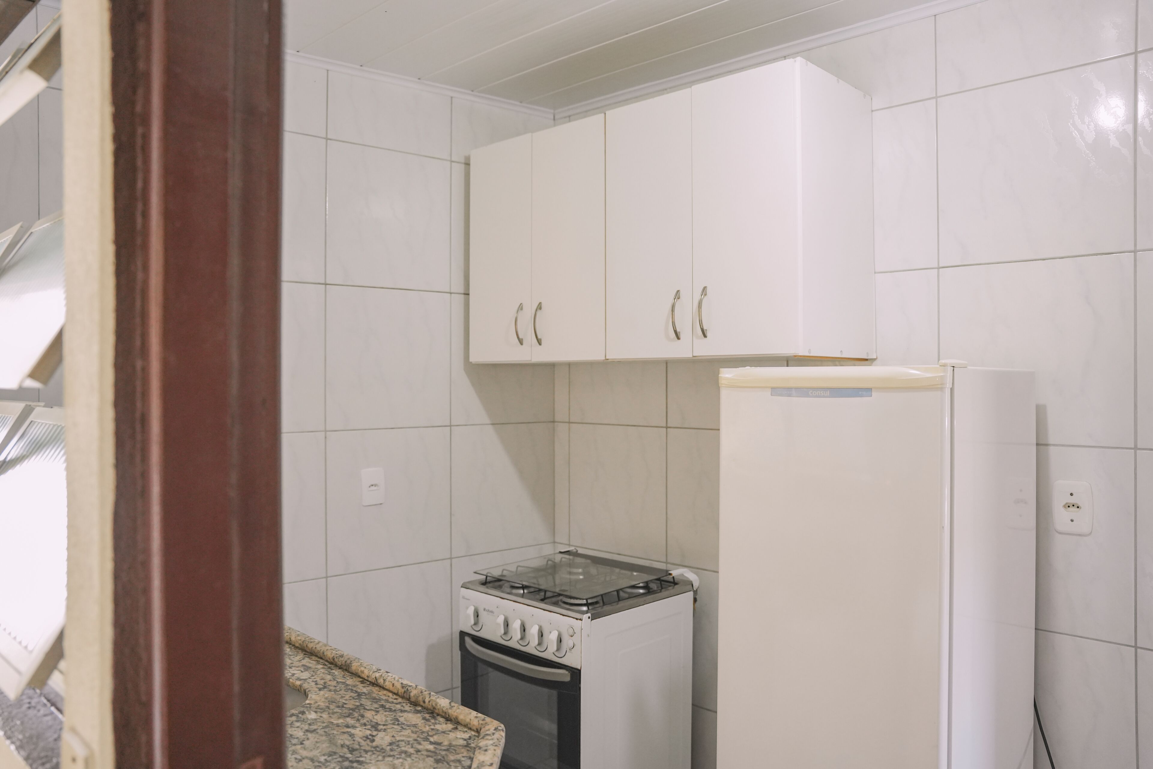 A compact kitchen with white cabinets, a gas stove, and a refrigerator.