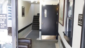 A hallway with a staircase, a door, and a bench. - Morinville Plaza & Suites (Morinville)