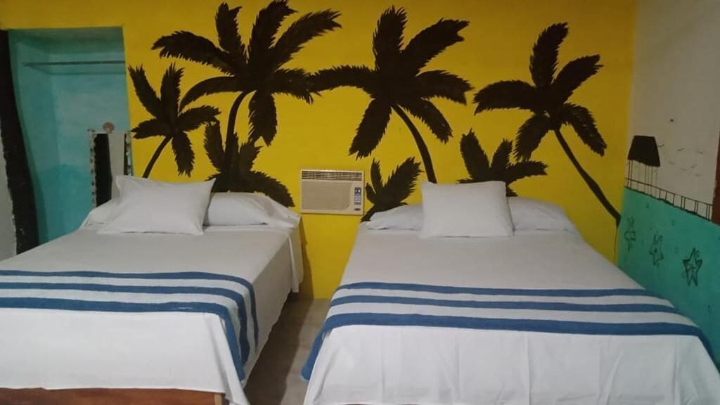 Una habitación con dos camas, un calentador de pared y una puerta.