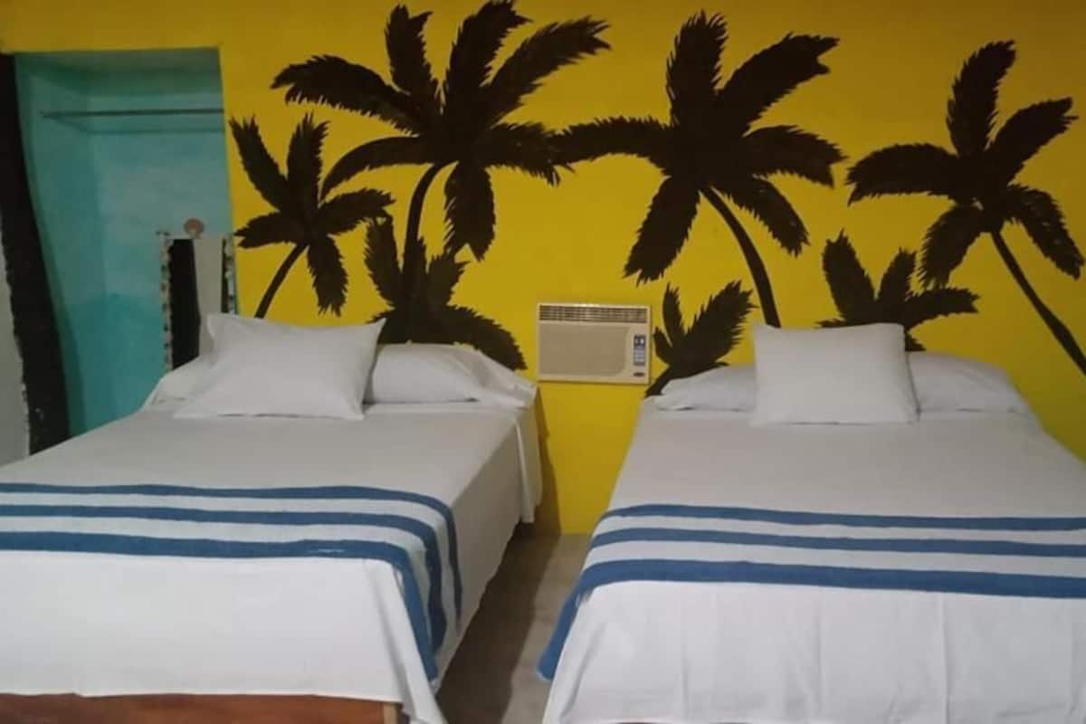 A room with two beds, a wall heater, and a door.