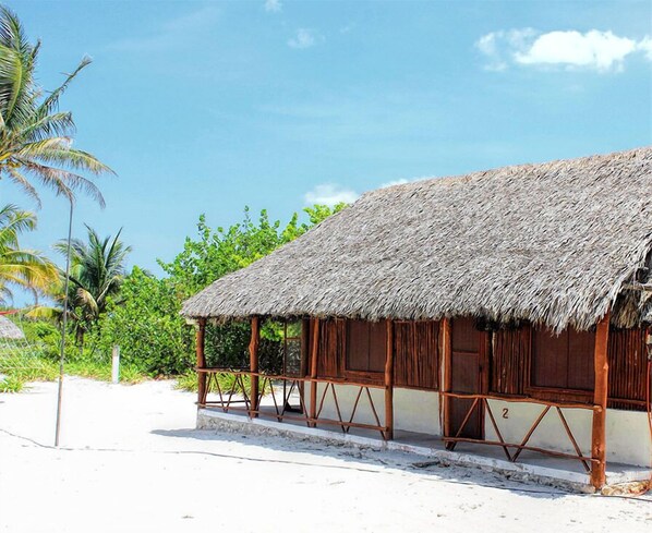 A thatched-roof hut with wooden walls and a sandy beach in the background. - Cabañas El Cuyo (El Cuyo)