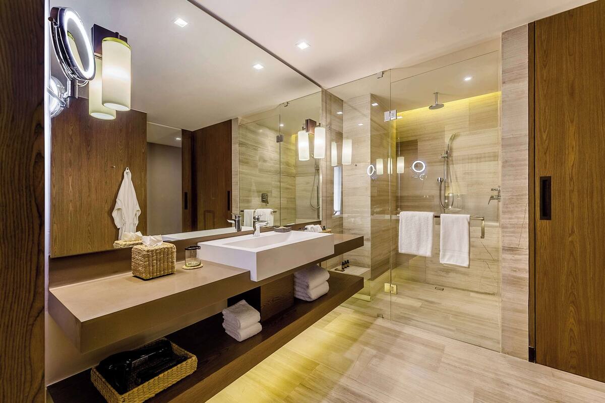 Une salle de bain moderne dotée d’un grand miroir, de deux lavabos et d’une douche à parois de verre.