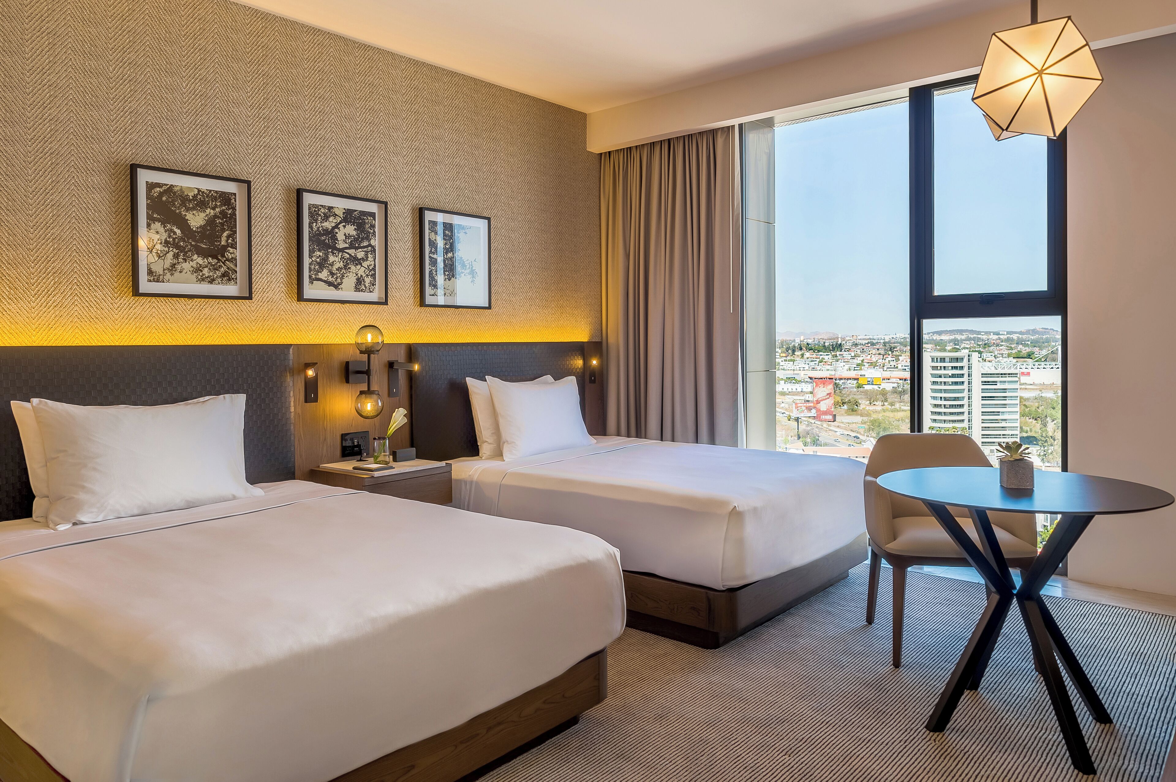 Une chambre d’hôtel avec deux lits, une table ronde et une vue sur la ville.