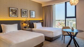 Une chambre d’hôtel avec deux lits, une table ronde et une vue sur la ville.