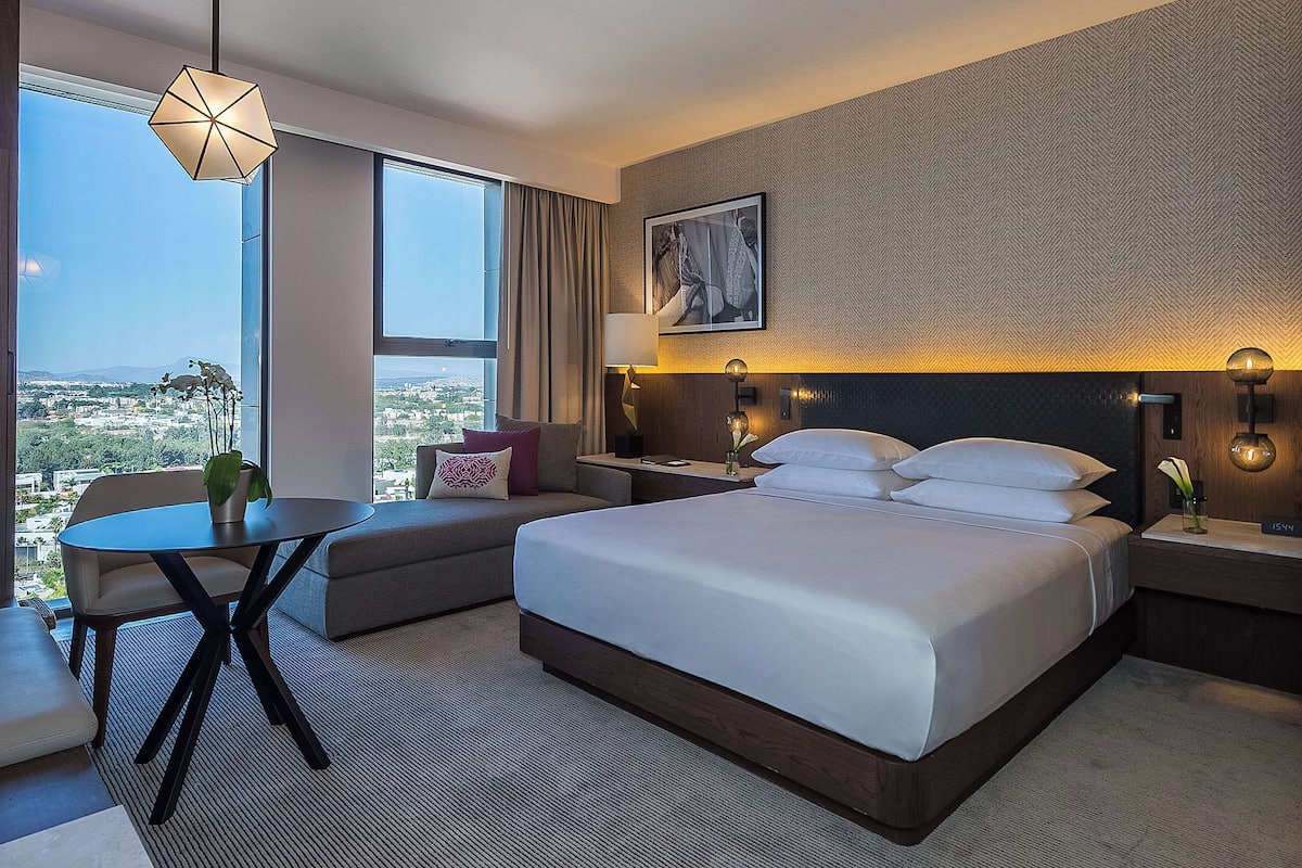 Une chambre d’hôtel avec un grand lit, un canapé, une table à manger et une vue sur la ville.