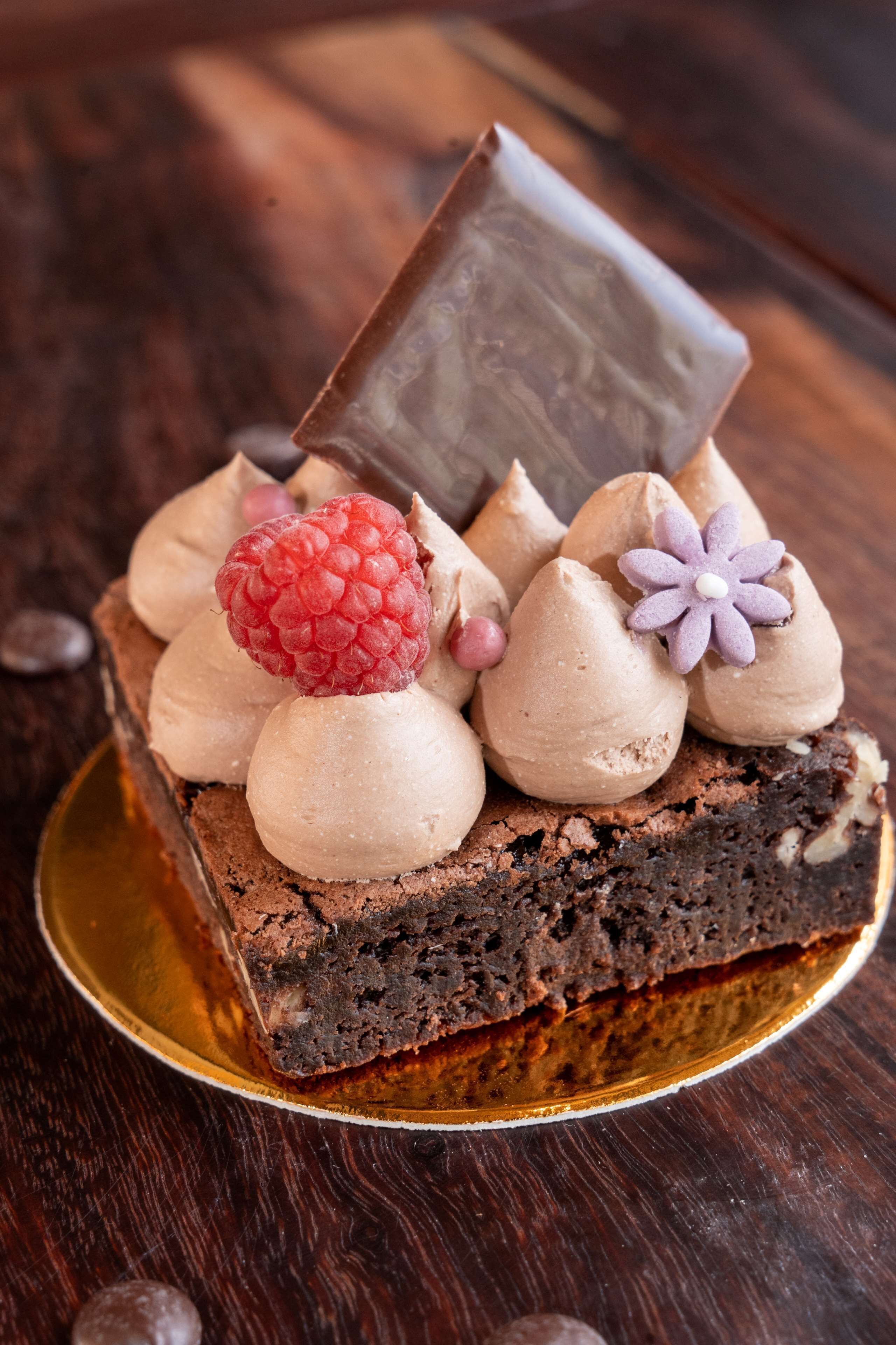 Una rebanada de pastel de chocolate con merengue y adornos sobre una superficie de madera.