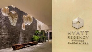 A modern lobby with a stone wall, a wooden bench, and a sign for the Hyatt Regency Andares Guadalajara.