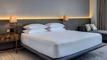 A hotel room with a large bed, two bedside tables, a sofa, and wall-mounted lamps.