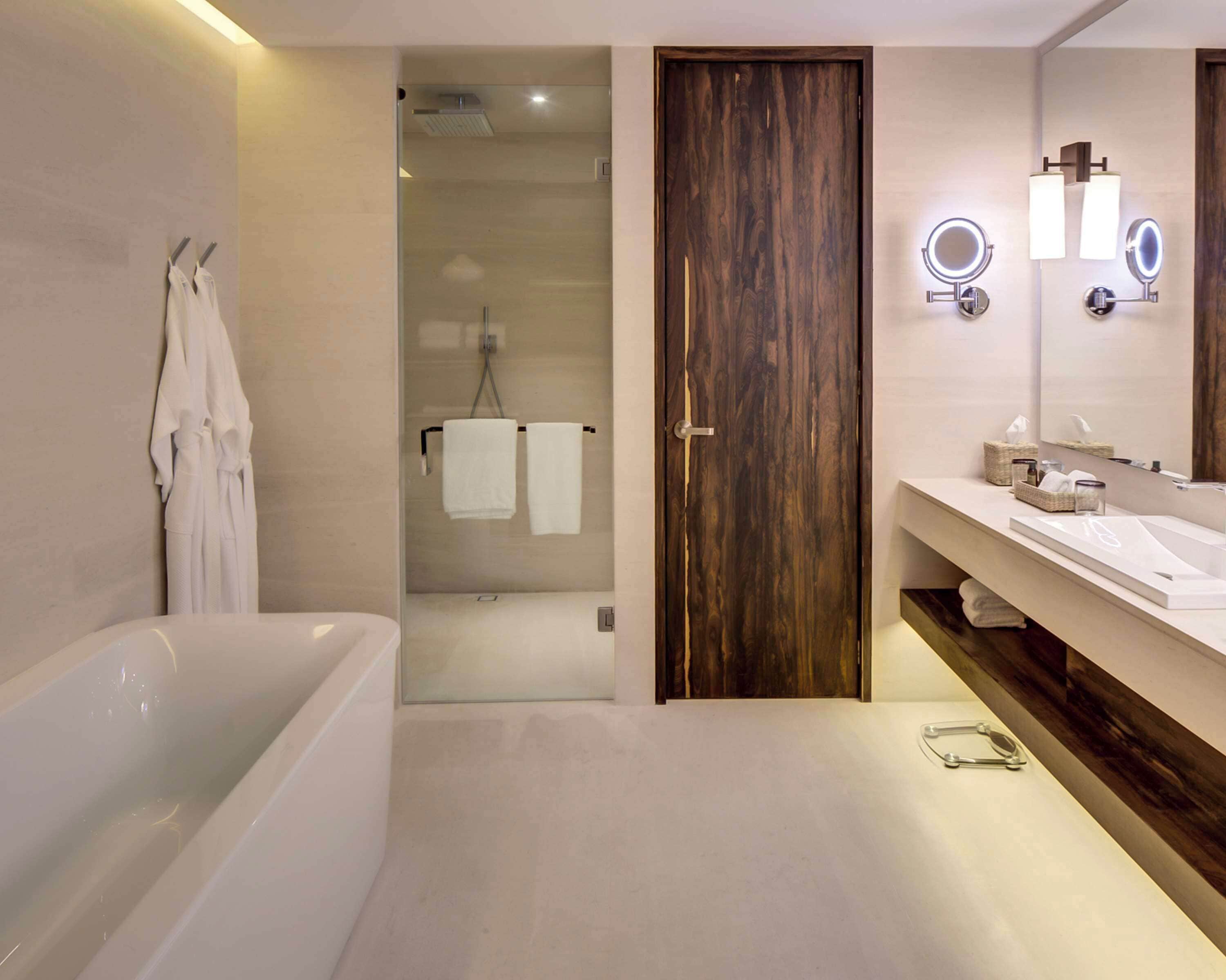 A modern bathroom with a bathtub, a glass-enclosed shower, and a vanity with a mirror and towel rack.