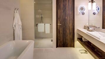 A modern bathroom with a bathtub, a glass-enclosed shower, and a vanity with a mirror and towel rack.