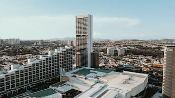 Un edificio alto con un diseño arquitectónico moderno, rodeado de otros edificios y un paisaje urbano al fondo.