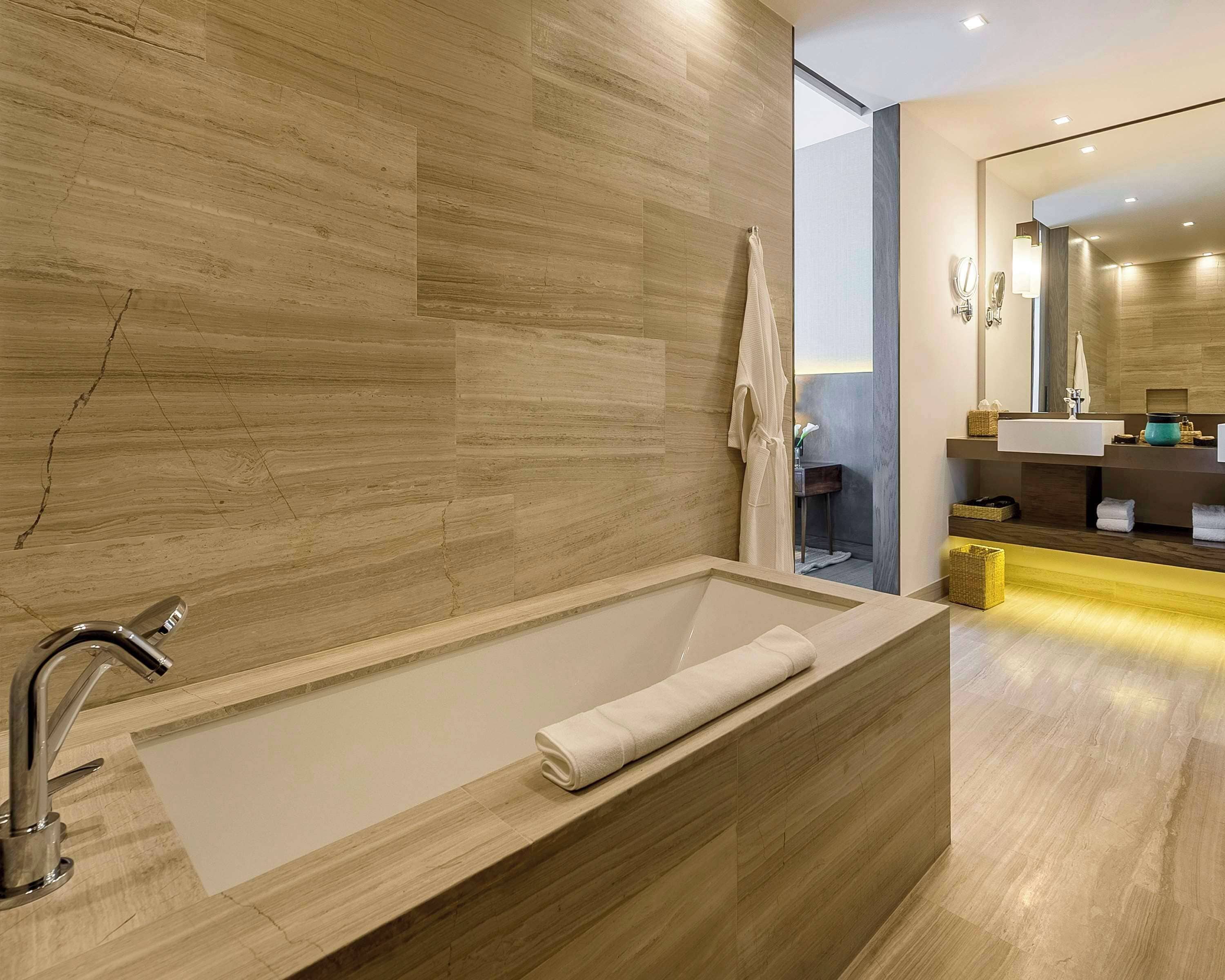 A modern bathroom with a large bathtub, a wooden vanity, and a mirror.