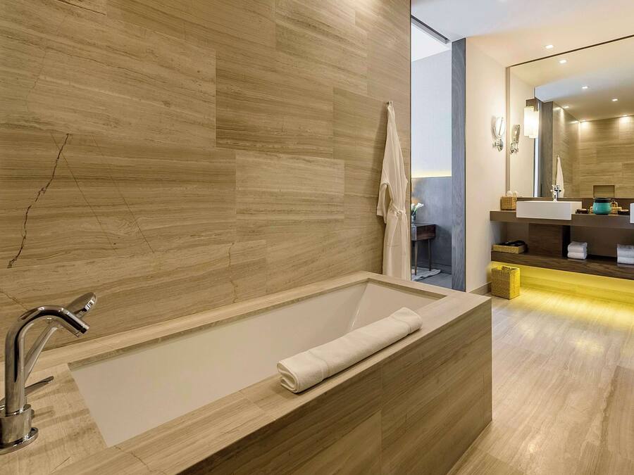 A modern bathroom with a large bathtub, a wooden vanity, and a mirror.