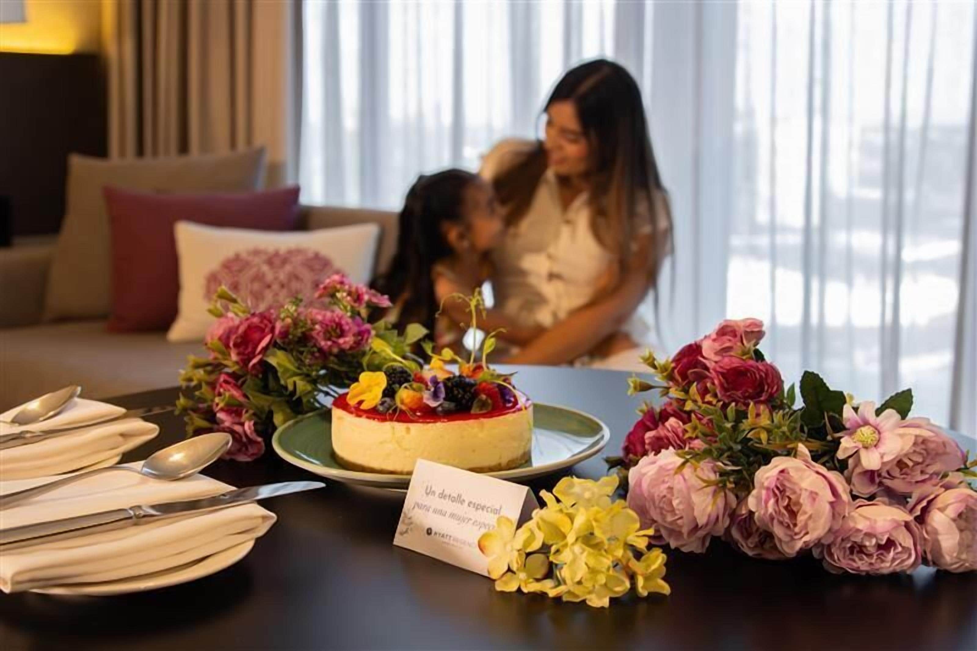 Una mesa de comedor con un postre, flores y un letrero.