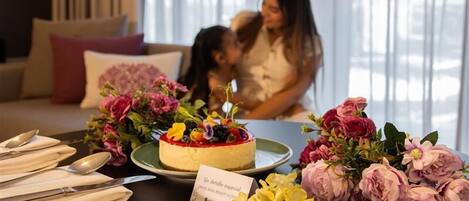 Una mesa de comedor con un postre, flores y un letrero.