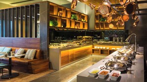 A modern restaurant with a long counter, a wooden seating area, and hanging copper pots.