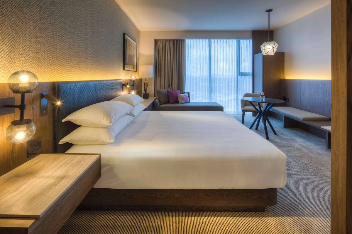 Une chambre d’hôtel avec un grand lit, un bureau, une chaise et une petite table.