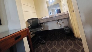 Une salle de bain avec un lavabo, un miroir et une chaise.