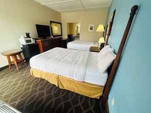 Een hotelkamer met een bed, een bureau met een computer, een stoel, een televisie en een lamp.