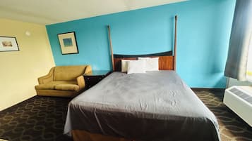 Habitación de hotel con cama, una silla, un cuadro en la pared y un equipo de aire acondicionado.