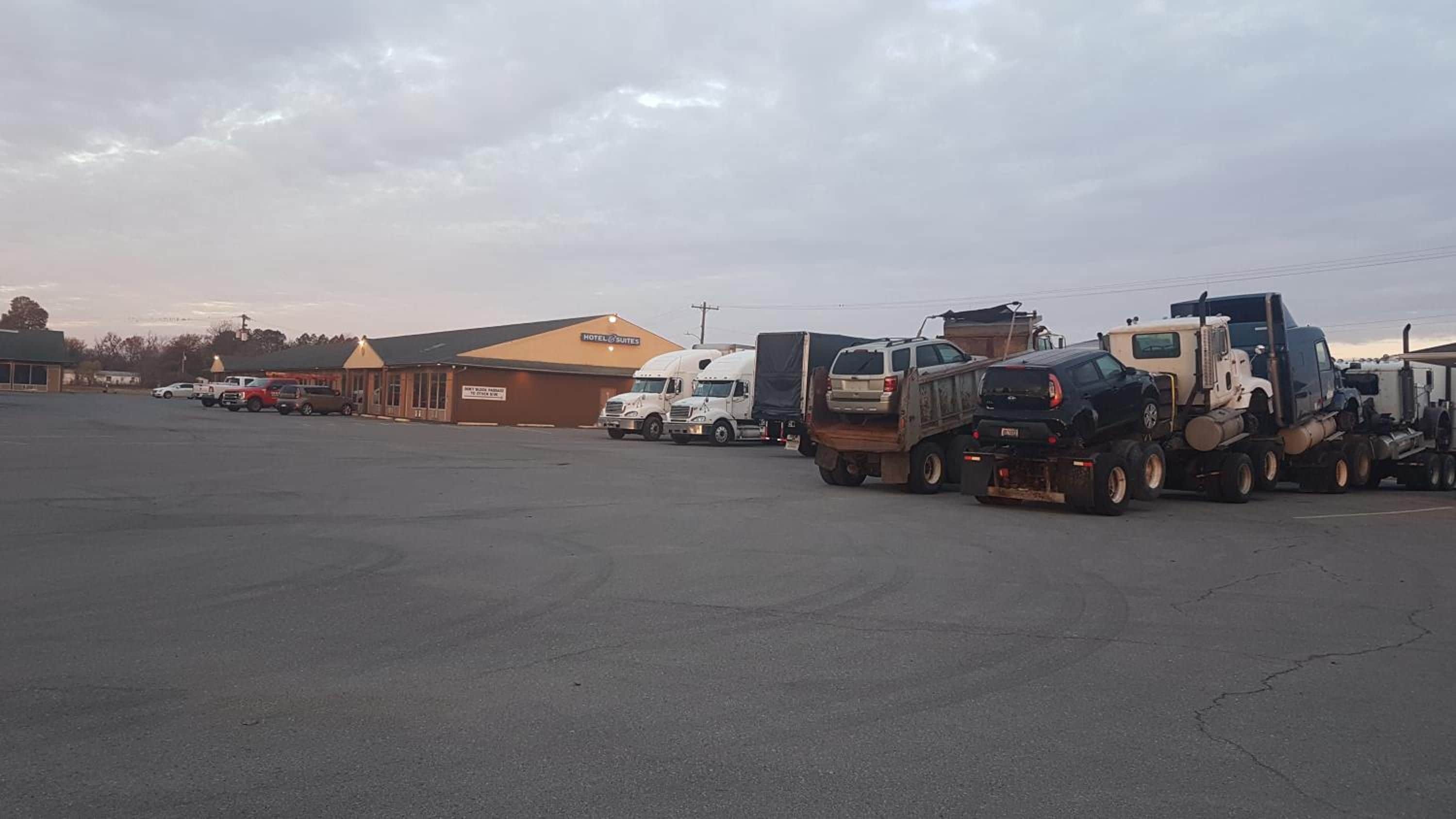 Un estacionamiento con varios camiones y un edificio con el letrero 'Hotel Suites' al fondo.