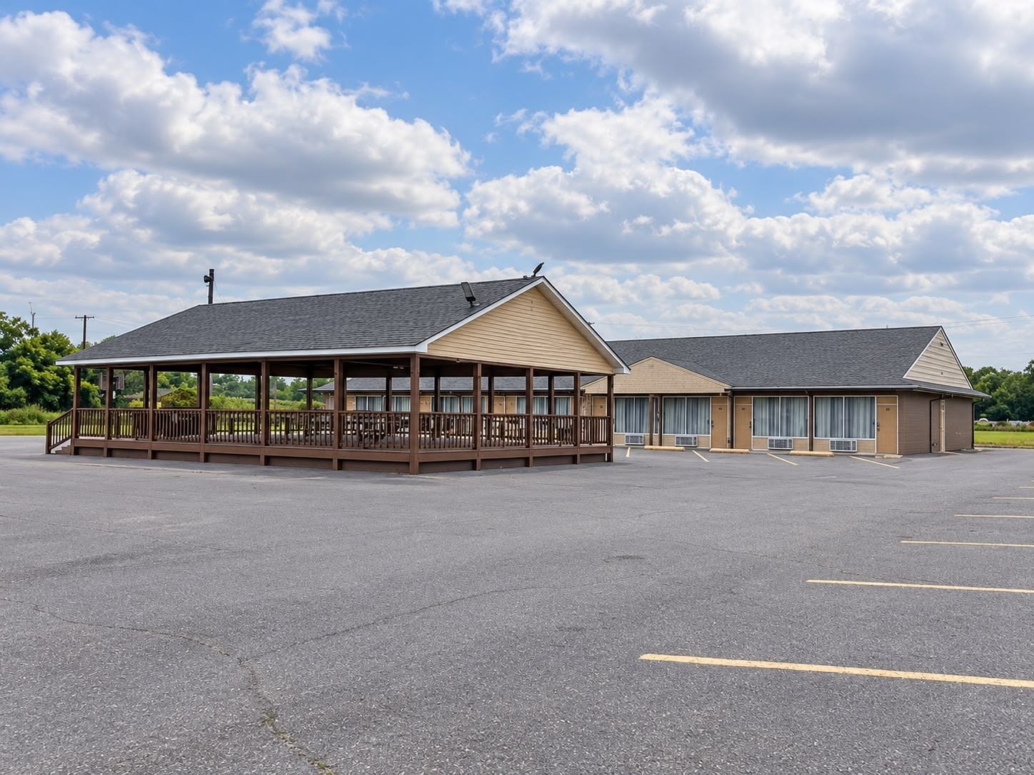 A motel with a covered outdoor seating area and a parking lot.
