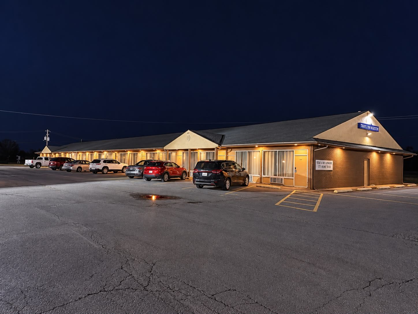 A motel with multiple rooms, a parking lot, and a sign indicating 'Travel Inn Marston.'