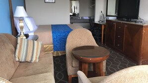 Une chambre d’hôtel équipée d’un lit, d’un bureau, d’une télévision et d’un coin salon avec une petite table.
