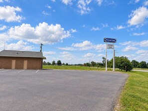 Ein Reisehotel mit Schild, das günstige Zimmer, einen Parkplatz und einen klaren Himmel anzeigt.