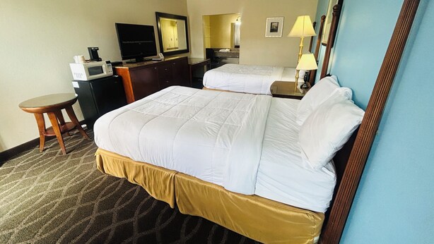 Une chambre d’hôtel avec deux lits, une télévision, un bureau et un miroir.