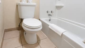 A bathroom with a toilet, a bathtub, and a toilet paper holder.