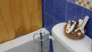 A bathroom with a white toilet, a shower curtain, and a blue tiled wall.