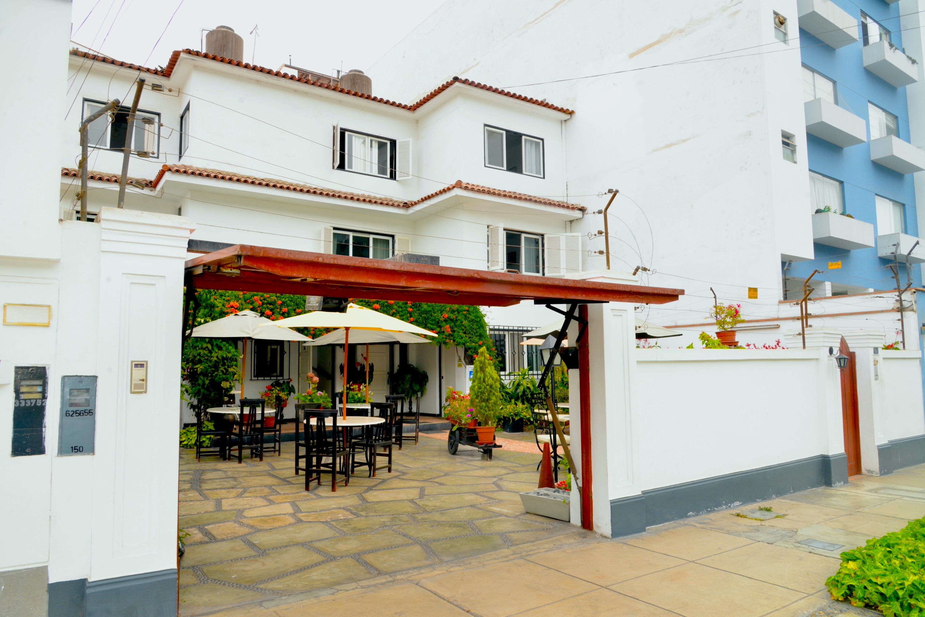A building with a covered patio area featuring outdoor seating and potted plants.