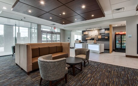 A modern lobby with a seating area, a kitchenette, and a refrigerator stocked with beverages.