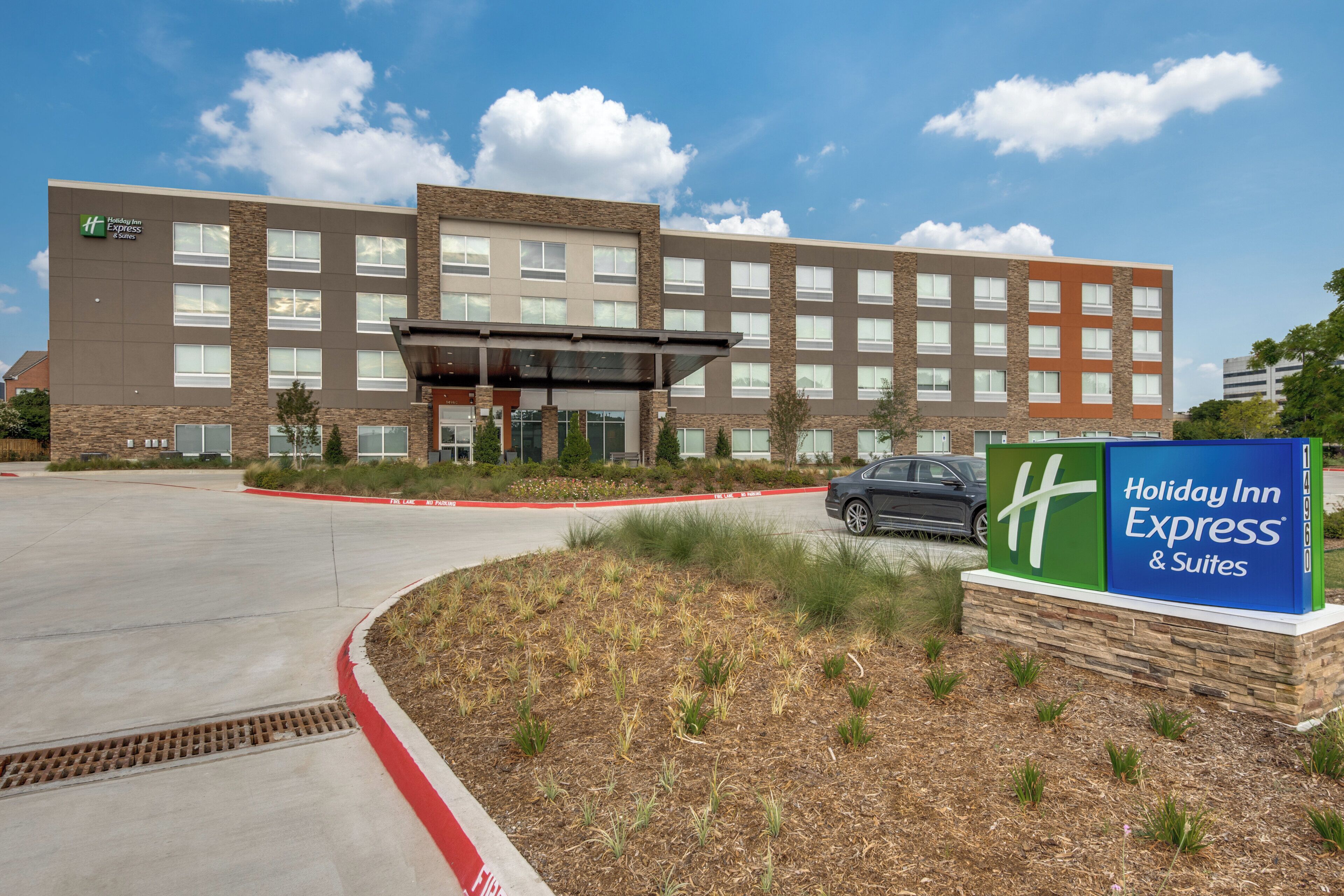 A Holiday Inn Express & Suites building with a clear sky and a parking lot.