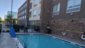 A swimming pool with a stone wall and a metal railing. - Holiday Inn Express & Suites Dallas North - Addison by IHG (Dallas)