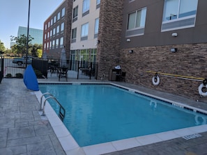Una piscina con un muro de piedra y una barandilla metálica.