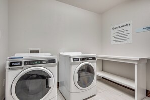 A guest laundry area with two front-loading washing machines and a sign detailing usage instructions. - Holiday Inn Express & Suites Dallas North - Addison by IHG (Dallas)