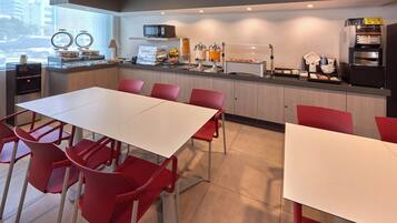 A modern kitchen with a white countertop, red chairs, and a large window.