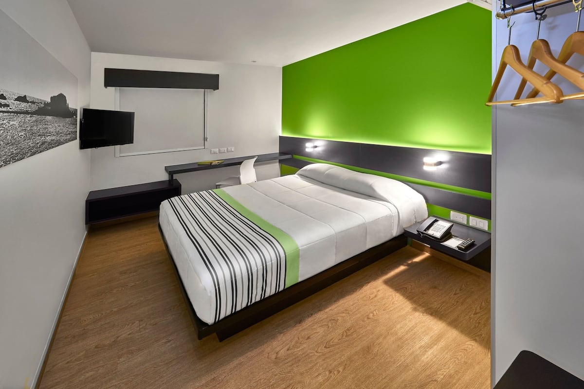Una habitación de hotel moderna con cama, mesita de noche y escritorio con silla.