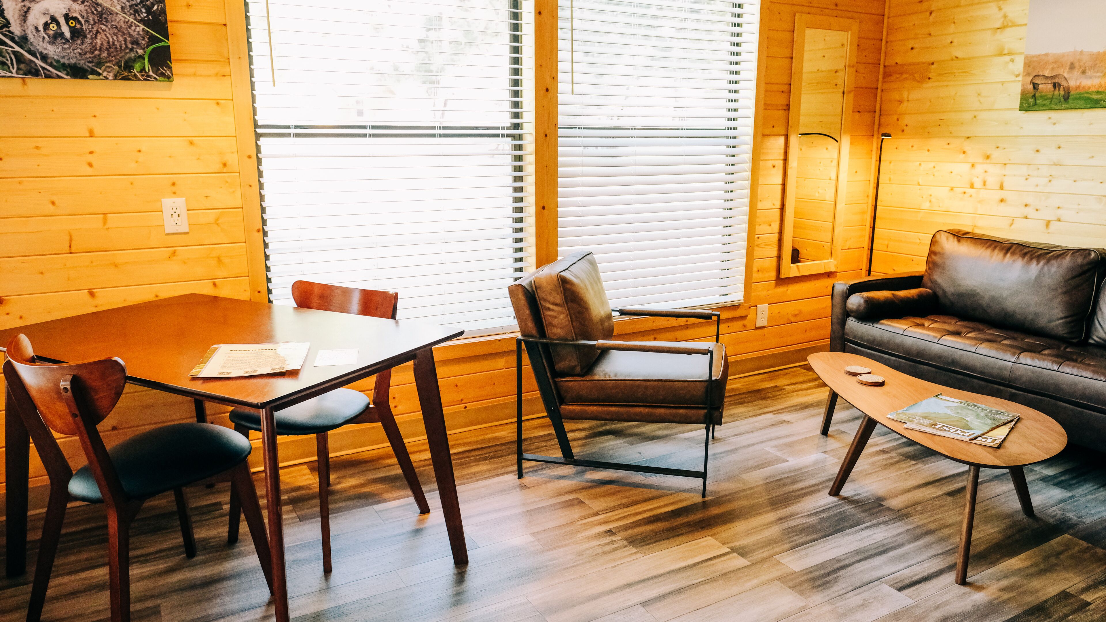 Ein gemütliches Zimmer mit Holzboden, einem Esstisch mit Stühlen, einer Couch und einem Couchtisch.